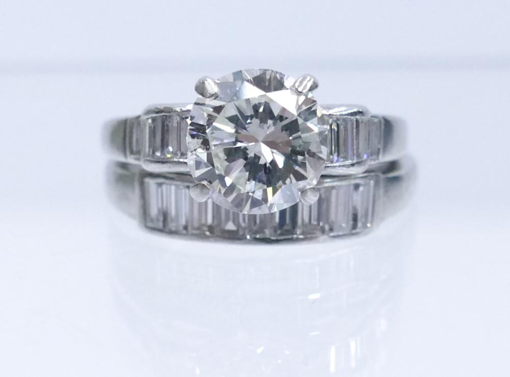 Close-up of a silver-toned diamond ring set with a large round center stone and baguette side stones.