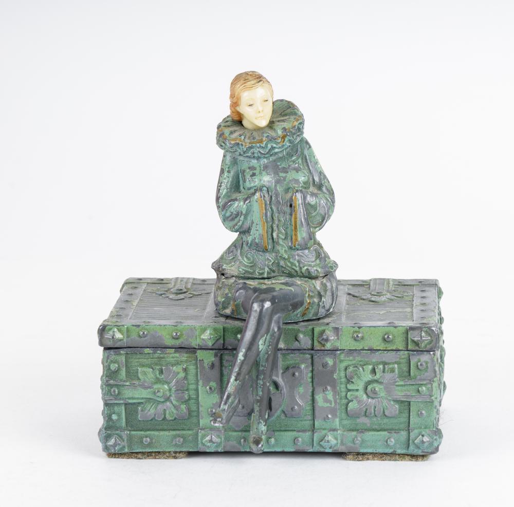 Green cast metal cigar box with decorative panels and a standing figure on top, shown on a light background.