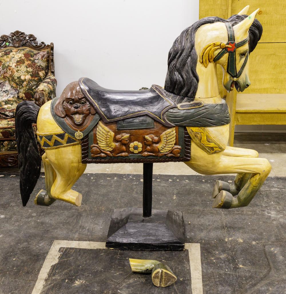Painted carousel-style horse figurine with a dark saddle and bridle, mounted on a wooden stand.