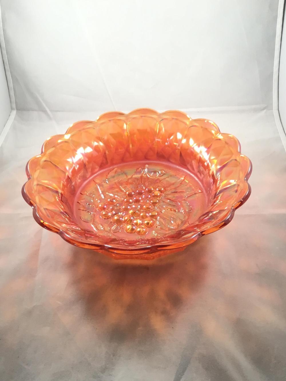 Amber orange carnival glass bowl with scalloped rim and raised decorative pattern inside.