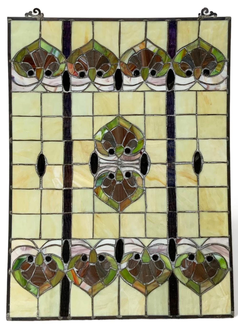 Close-up of a leaded stained glass window panel with yellow glass squares and repeating green and brown bird-like shapes.