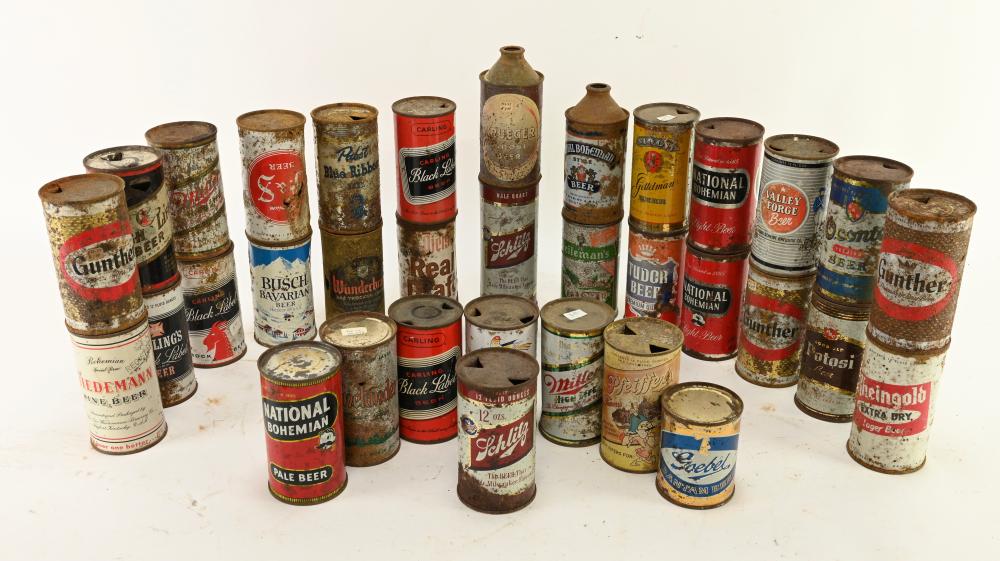 Collection of vintage metal beer cans and can tops standing in rows on a white background.