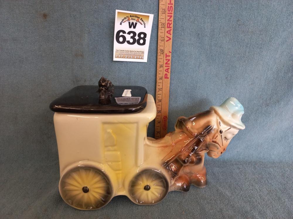 Cream and brown ceramic cookie jar shaped like a dog pulling a cart, with wheels and a small figurine on the lid.