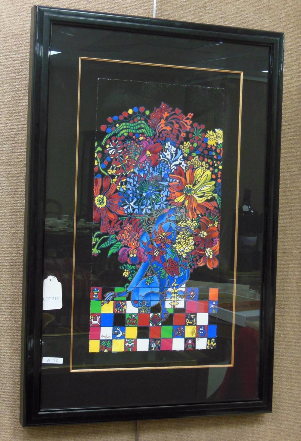 Framed colorful serigraph print showing a blue-haired woman holding or surrounded by flowers, with a decorative patterned border and checkerboard area at the r