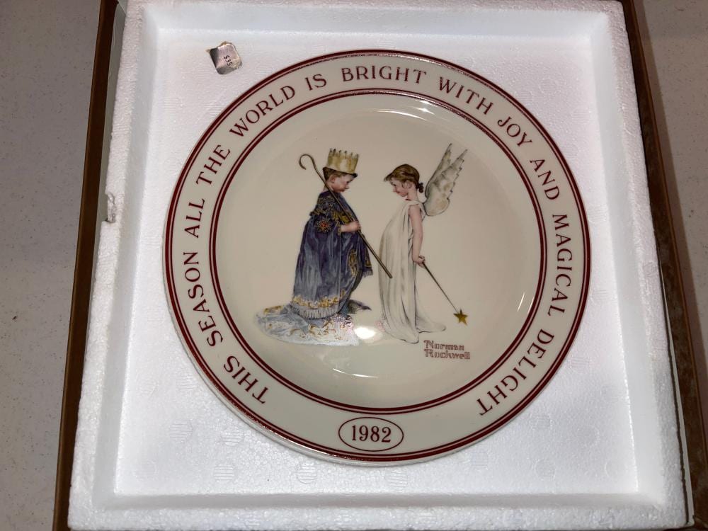 Collector decorative ceramic plate in a box, featuring two angel-like figures and a red border text reading “THE WORLD IS BRIGHT WITH JOY AND MAGIC.”