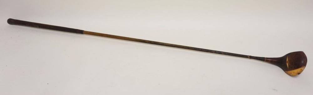 View of a single golf club with a dark metal shaft and a wooden head, photographed on a plain background.