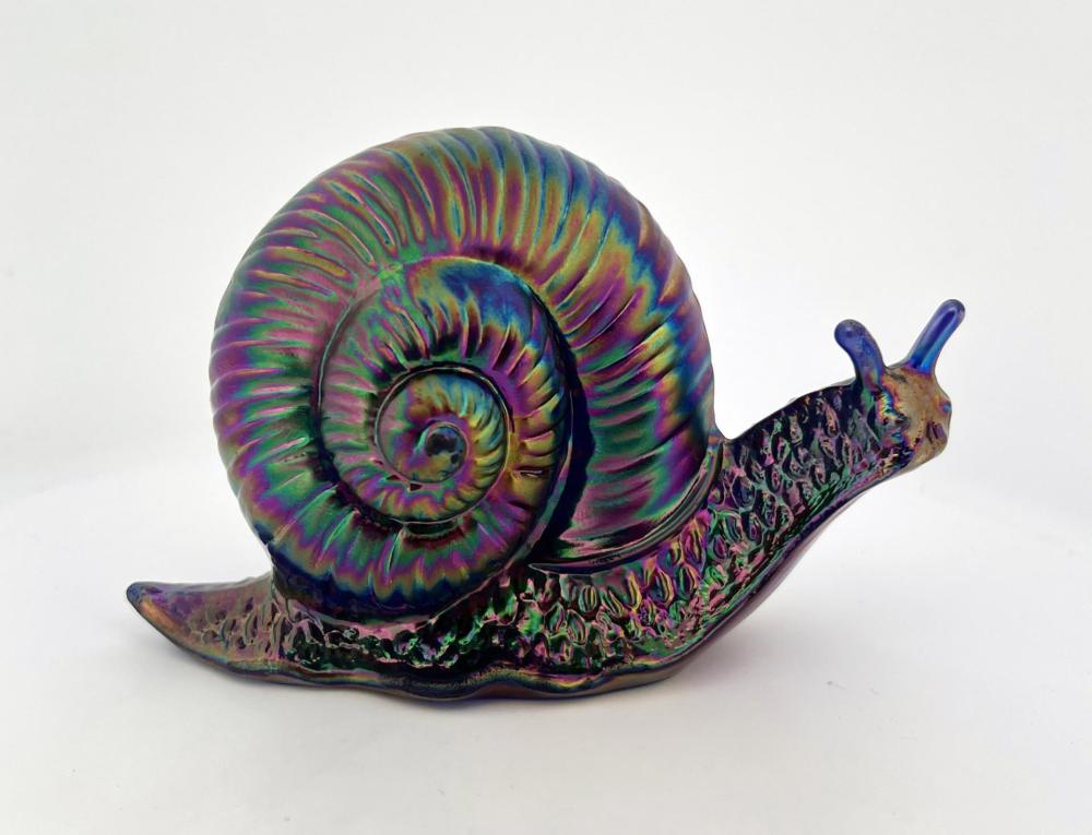 Colorful iridescent glass snail paperweight with a spiral shell and curled body on a white background.