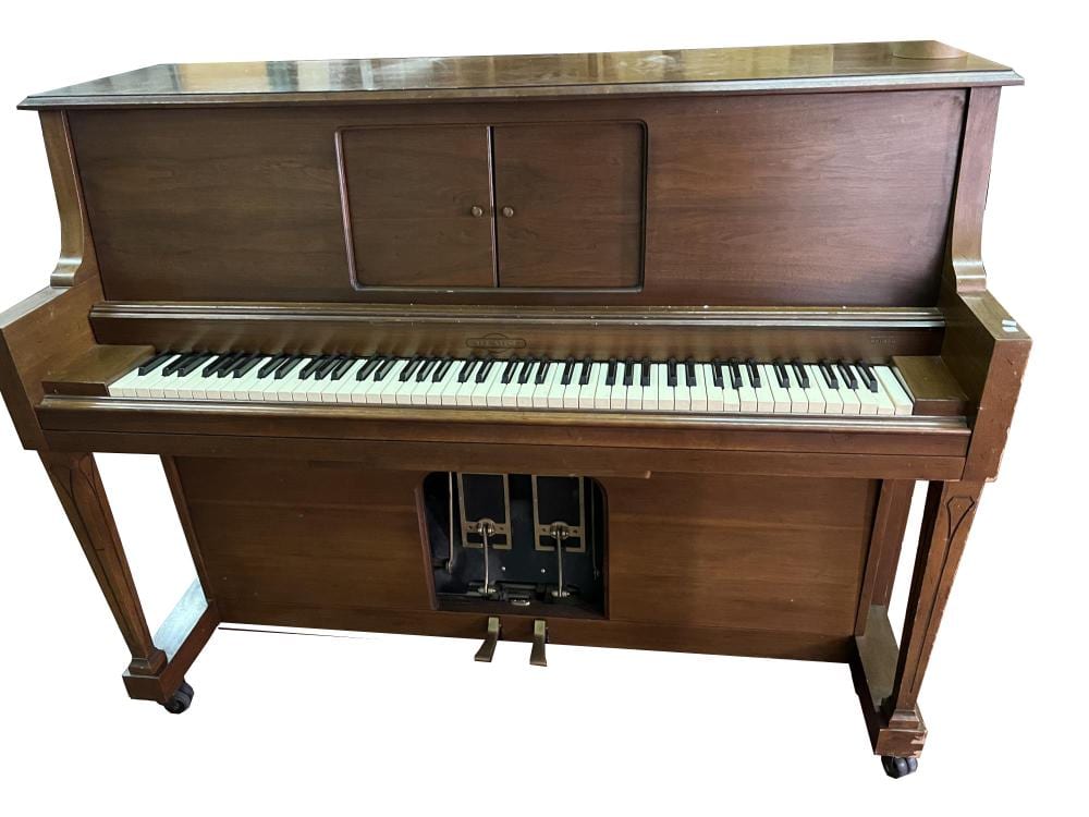 Vintage upright piano with a closed music cabinet and visible keyboard, front panel, and keys.