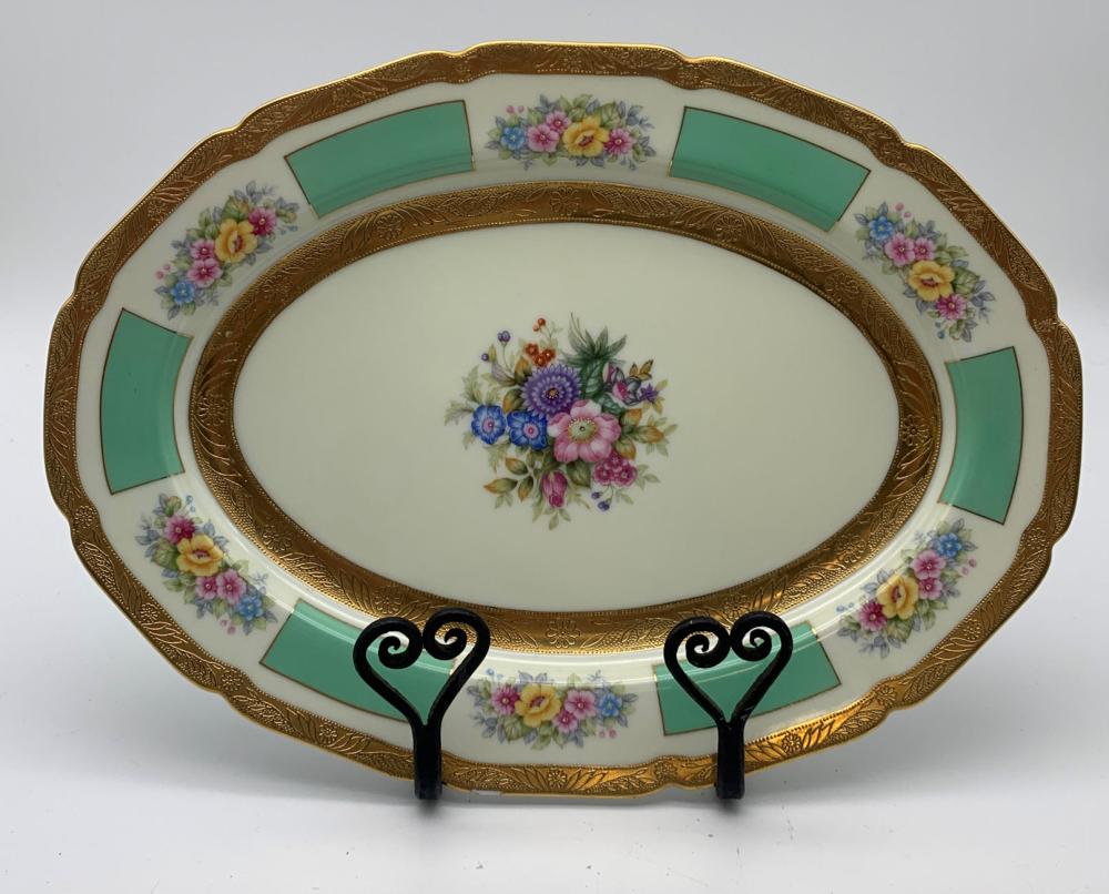 Porcelain serving tray with an oval center and gold gilt border, featuring a colorful bouquet of pink, blue, and yellow flowers and green geometric insets.