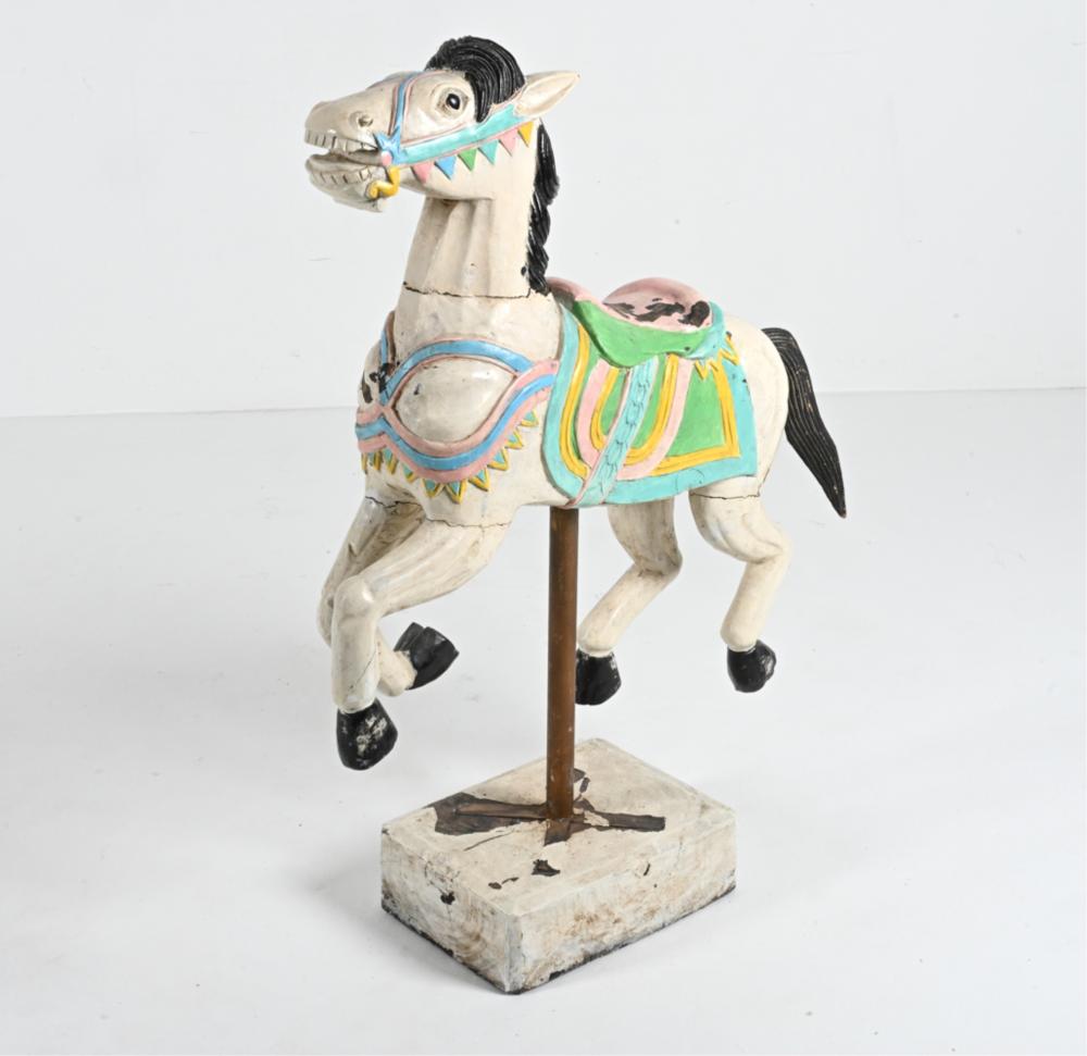 Painted hand-carved carousel-style horse figurine on a wooden base, standing and facing left against a white background.