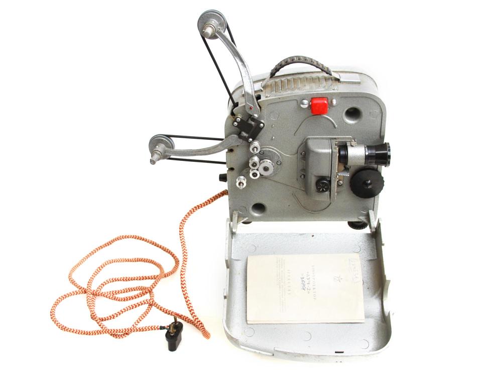 Gray vintage film projector with side control assembly, red switch, and orange cord, shown open on a light background.