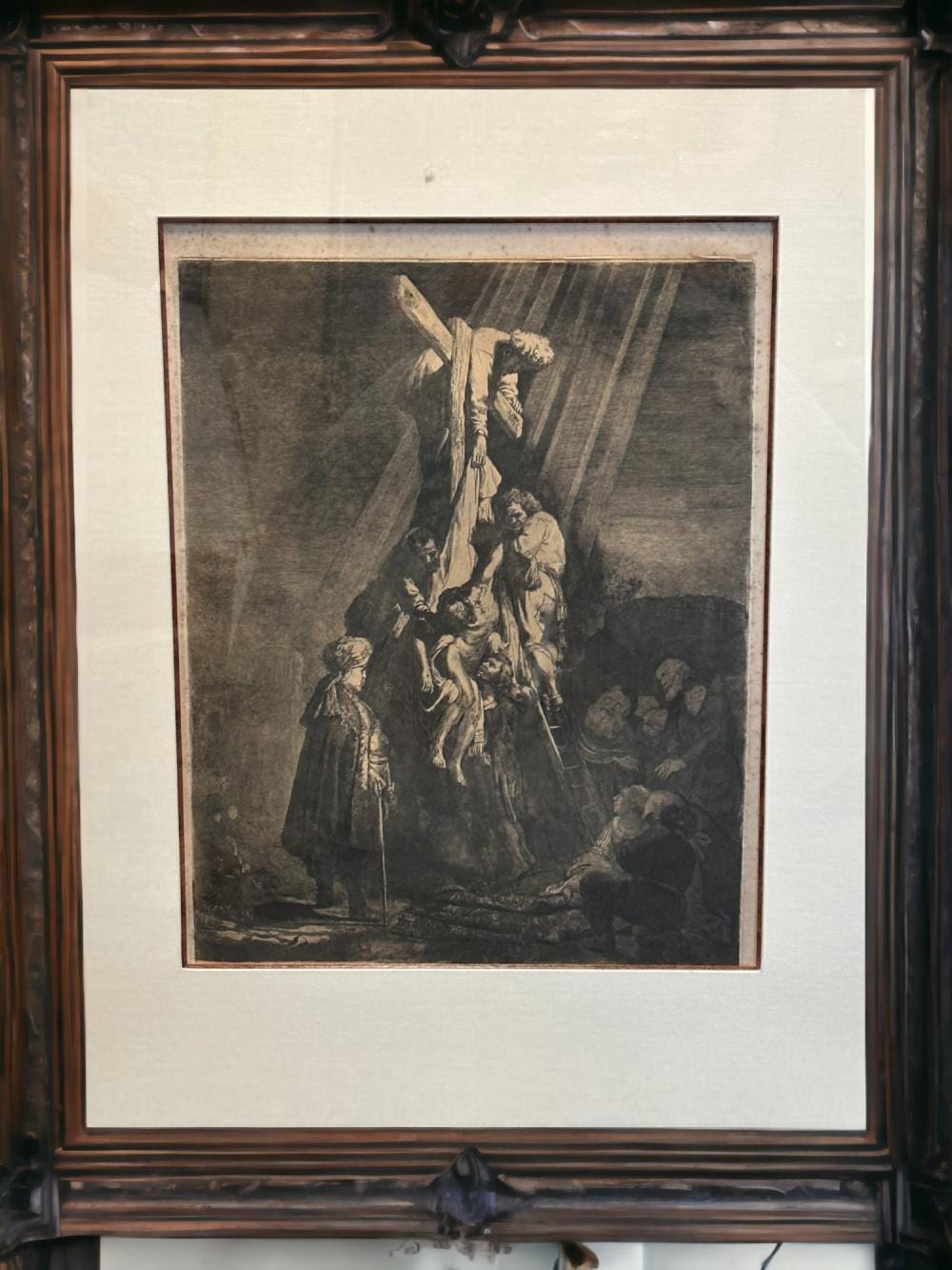 Framed black-and-white etching print showing a group gathered around a figure being taken down from a large cross.