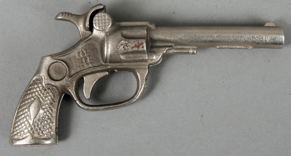 Metal cap gun toy shaped like a revolver with engraved grip and circular trigger guard, shown side view on a light background.