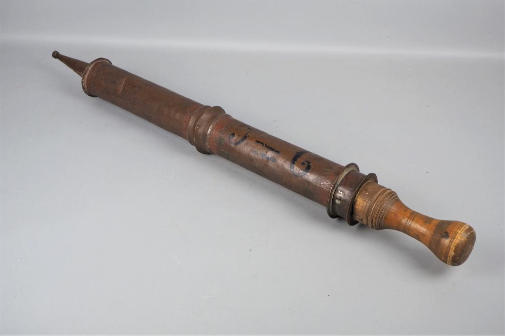 Small cylindrical copper fire extinguisher container with a long spout on one end and a capped base on the other, photographed on a light background.
