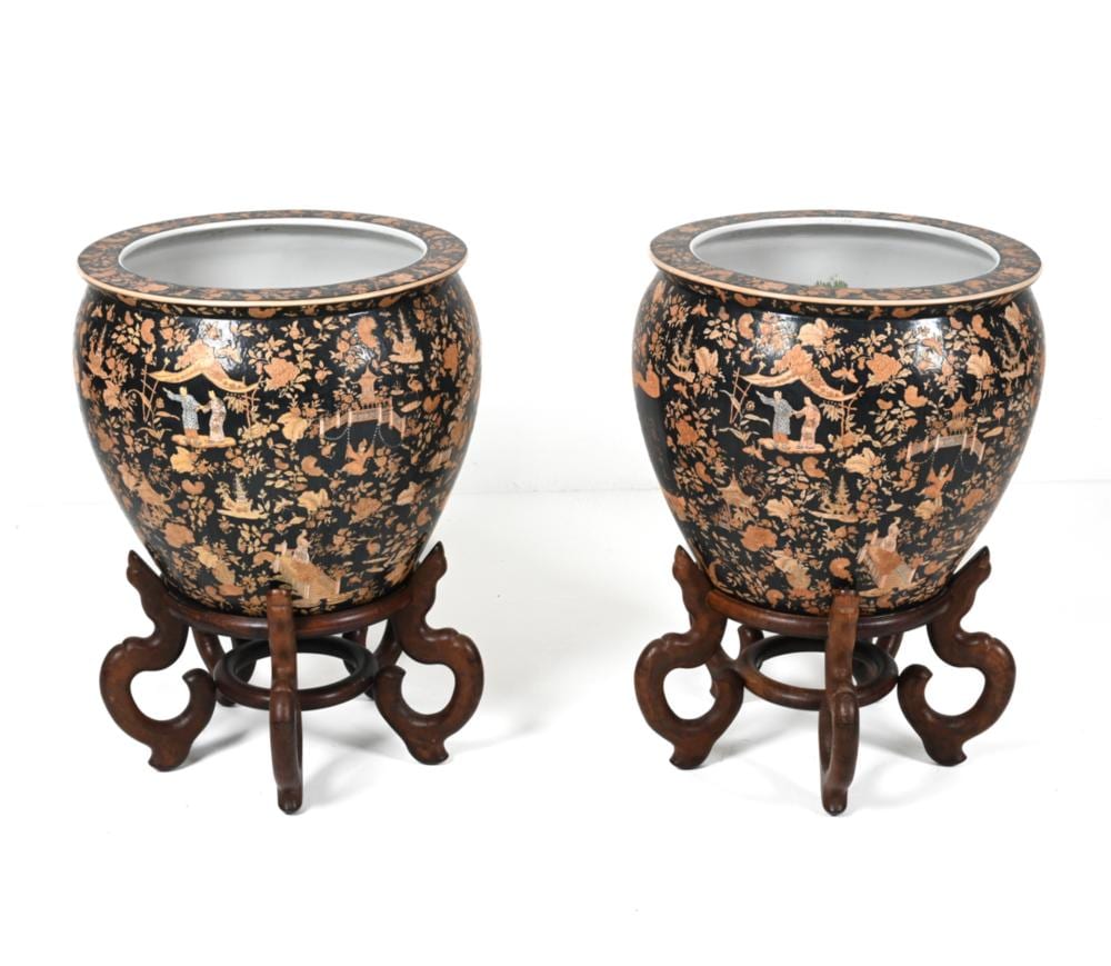 Pair of dark ceramic jardinieres with gold and orange floral and court-scene decoration, each on a dark wooden stand.
