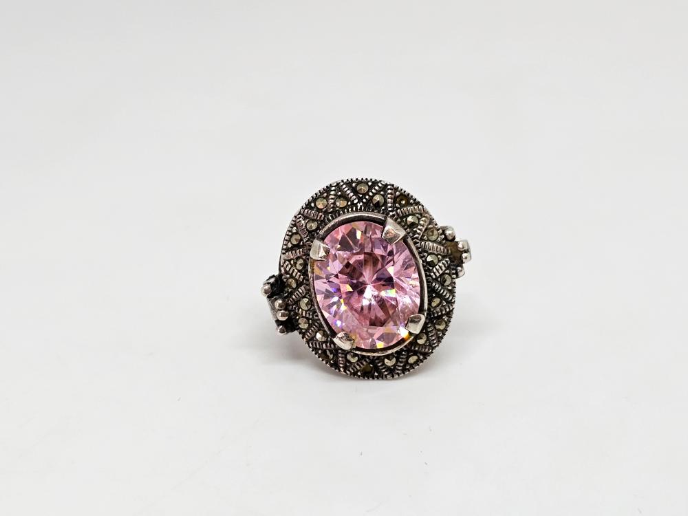 Silver-tone oval gemstone ring with a large pink crystal surrounded by a dark metal halo and small dark stones