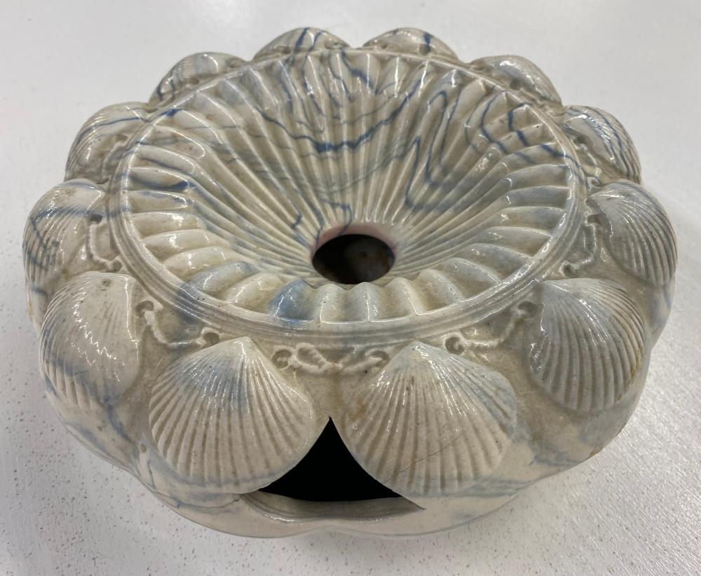 Glazed ceramic spittoon or vase-shaped container with ridged scallop pattern and a wide central opening, in white with blue-gray marks.