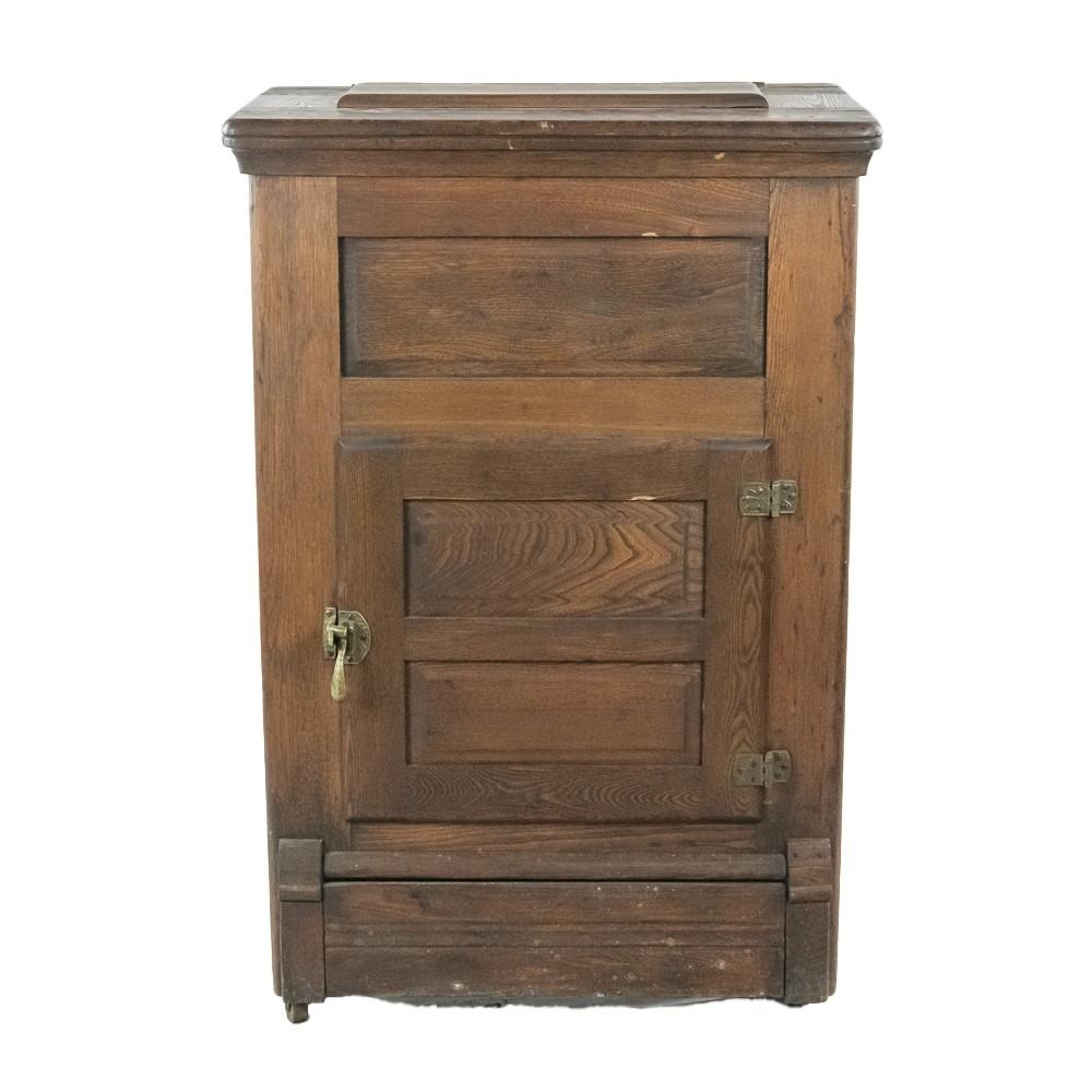 Small wooden ice box or cabinet with a hinged front door, metal hinges, and a lidded top on simple legs.