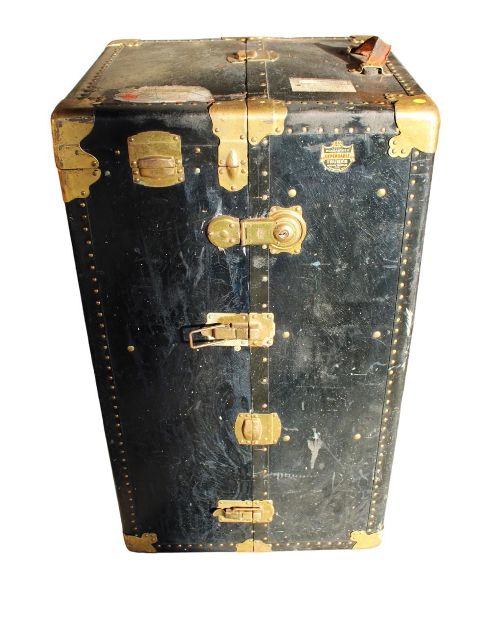 Front view of a vintage steamer trunk with black leatherette panels, brass corner guards, studs, and metal locks and latches.
