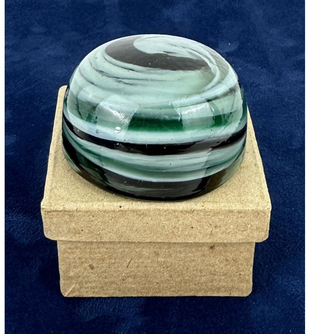 Green and white swirled glass marble-like paperweight with a curved dome on a beige display block.