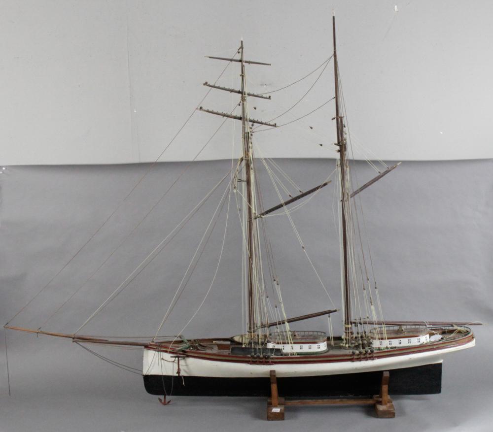 Detailed miniature sailing ship model with white hull and rigging on a wooden display stand.