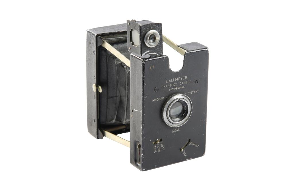 Front view of a vintage box camera with a metal lens housing and engraved Dallmeyer Snapshot Camera markings on a dark body.