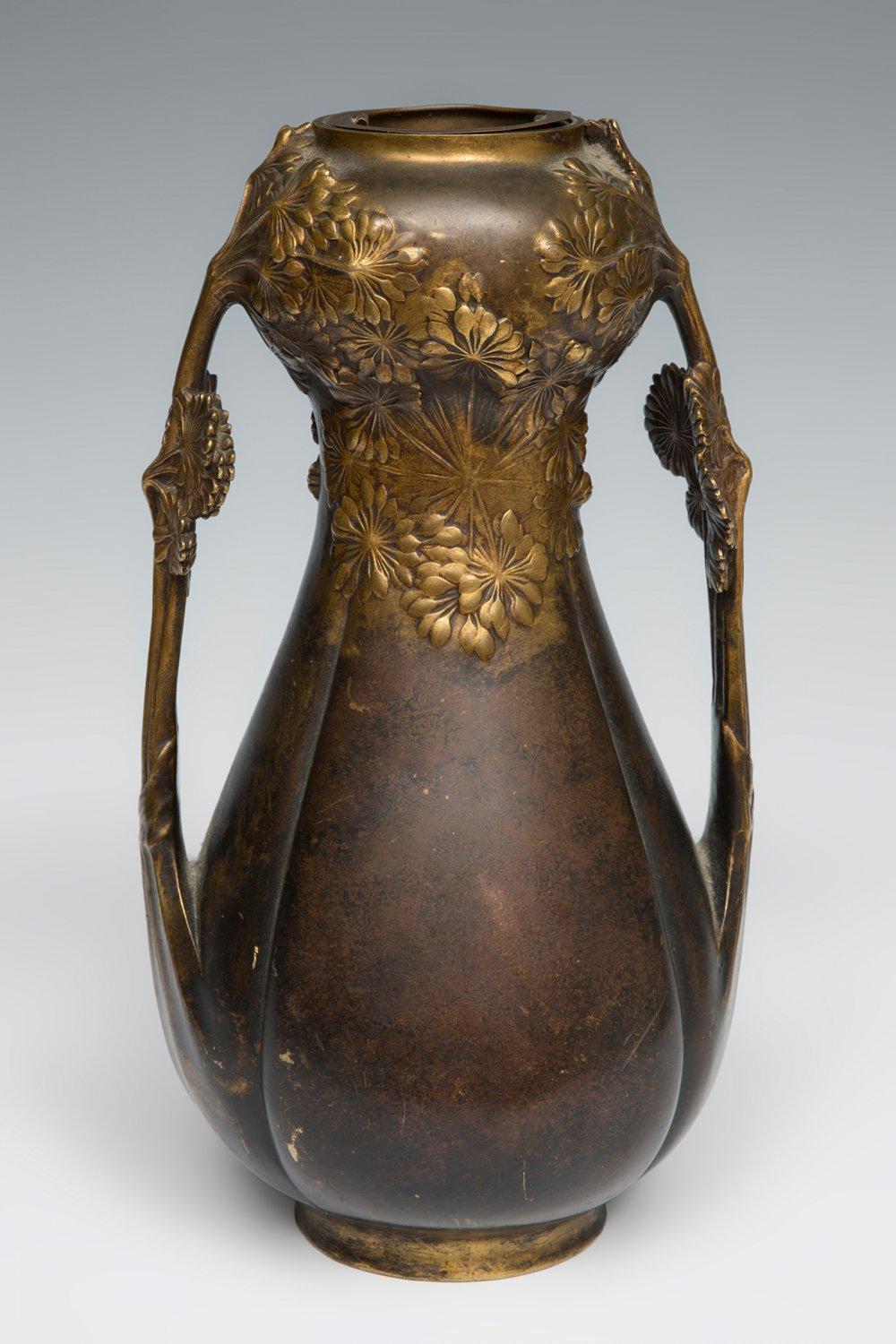 Bronze vase with an open top and wide handles, decorated with raised floral reliefs and a dark brown and gold patina.