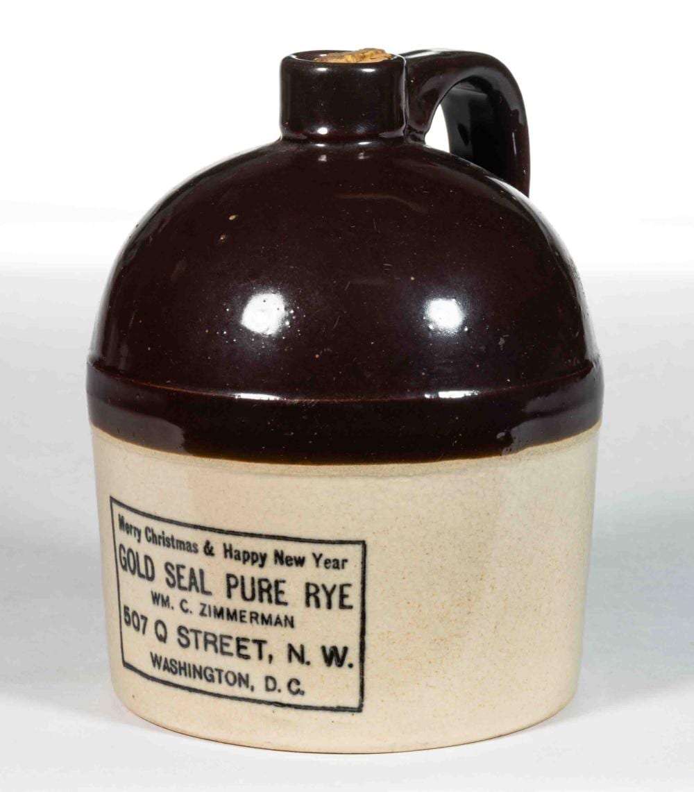 Brown and cream stoneware advertising whiskey jug with a printed label reading “GOLD SEAL PURE RYE,” “WM. C. ZIMMERMAN,” and “WASHINGTON, D.C.”