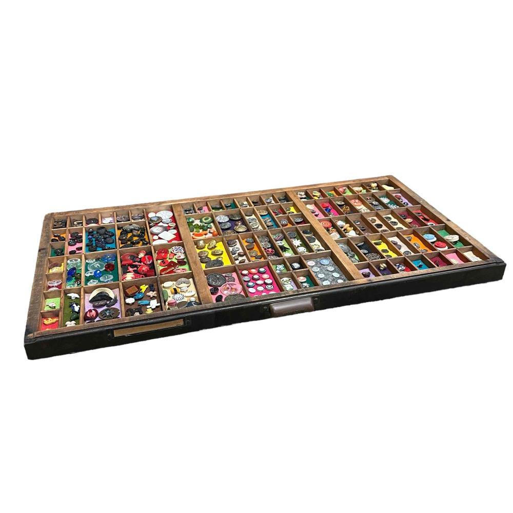 Wooden tray filled with many colorful decorative buttons in divided compartments.