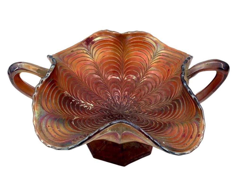 Red and amber footed carnival glass candy dish with leaf-like feathered pattern and two side handles.
