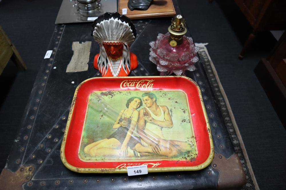 Vintage red Coca‑Cola tin tray with a printed image of two people in swimsuits inside a yellow frame, photographed on a dark surface.