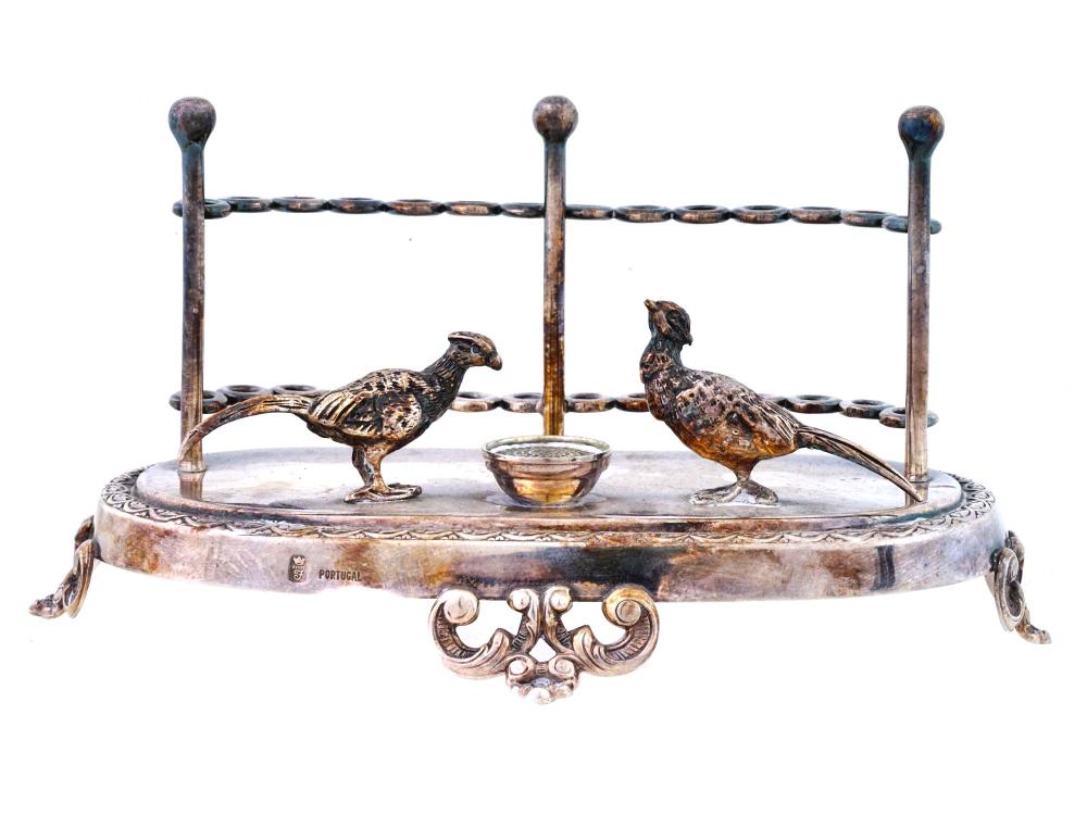 Silver-colored toothpick holder with two bird finials on a round base and a central small cup, on a white background.