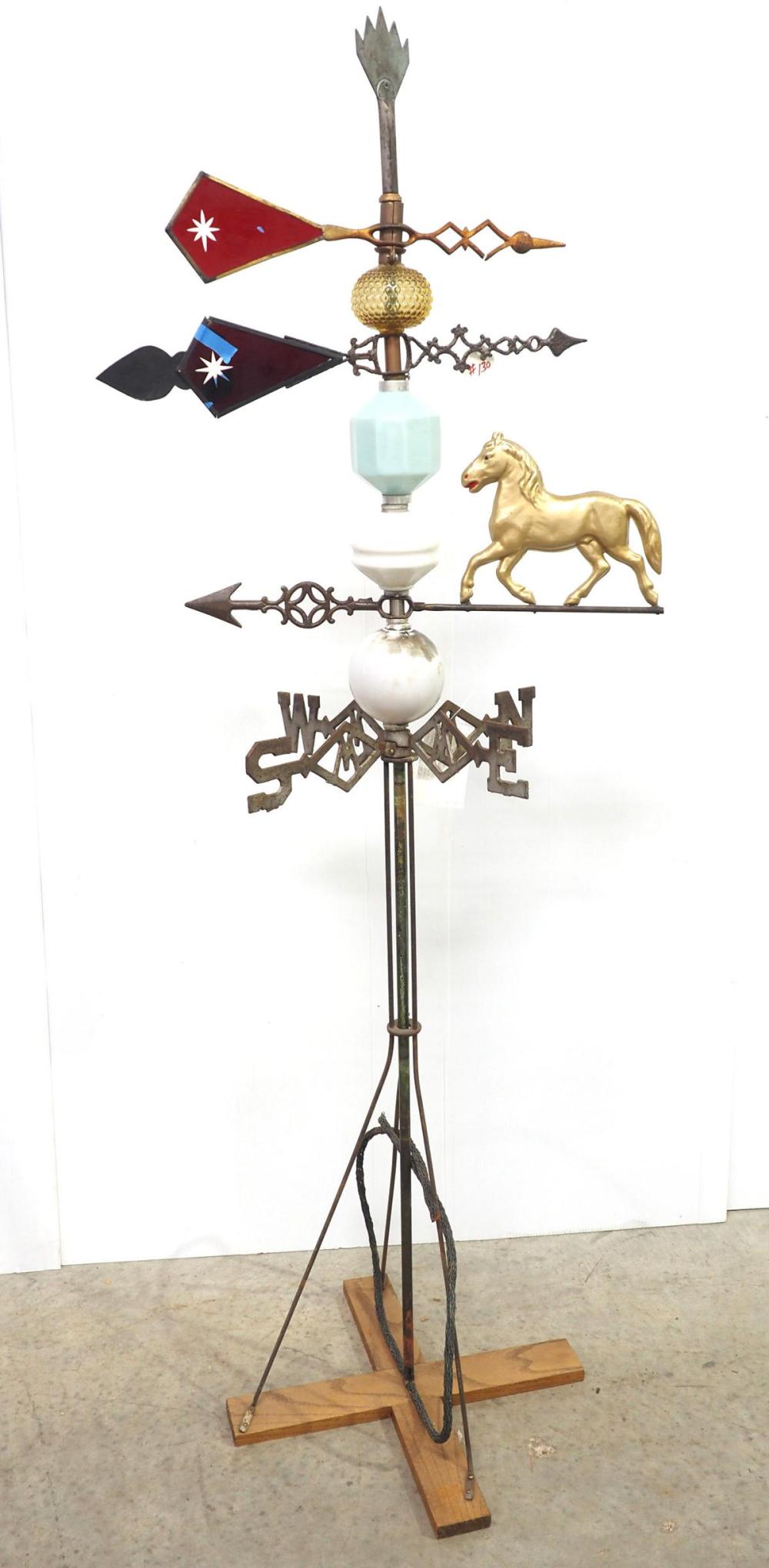 Metal horse weathervane with a gold horse figure and red and blue arrow signs on a decorative pole stand.