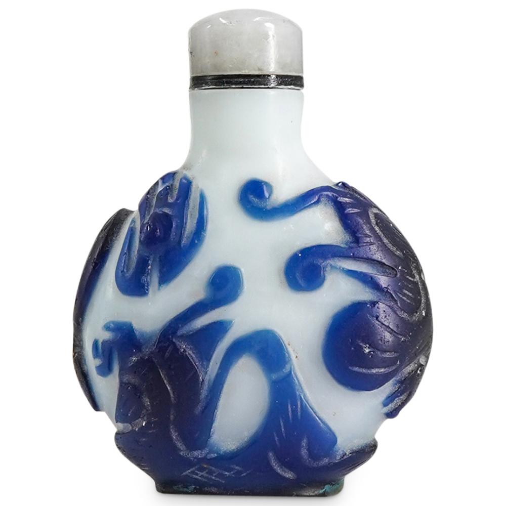 Small rounded glass snuff bottle with a light body, blue painted decoration, and a darker blue stopper area at the top.