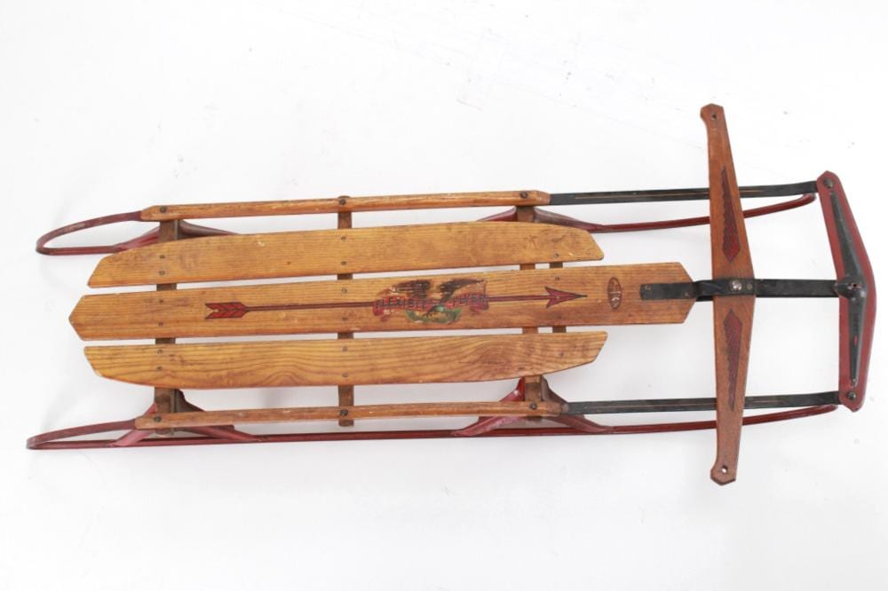 Wood and black metal flexible snow sled with curved wooden runners and a red frame, viewed from the side.