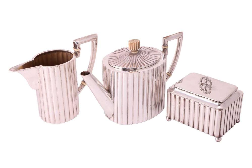 An Art Deco three-piece tea service, comprising a tea pot of oval form with reeded body, the hinged cover featuring an ivory finial; a milk jug of reeded body with angled handles featuring ivory insulators and a rectangular box with reeded body,... sold by Dawsons Auctioneers, lot 319 — auction record photograph