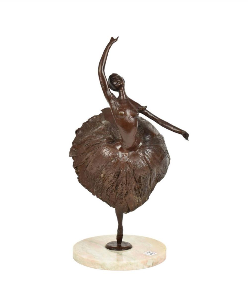 Patinated bronze sculpture of a ballet dancer with one arm raised, wearing a textured skirt and standing on a round stone base.