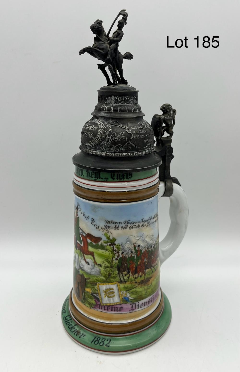 Antique ceramic beer stein with painted soldiers and landscape scenes, dark metal lid with figurine finial, and green base ring.