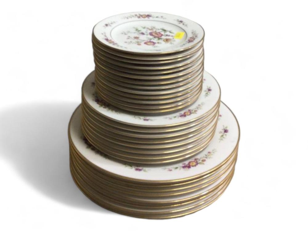 Stacked porcelain dinner plates with gold rims and small floral bouquets around the outer edge.