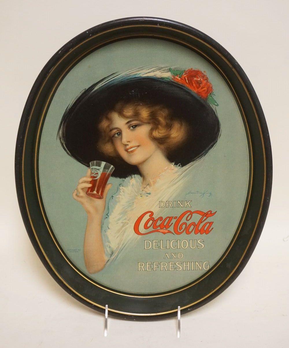 Round vintage Coca-Cola tin serving tray featuring a smiling woman in a dark hat holding a red drink cup, with the text “Drink Coca-Cola Delicious and Refreshin