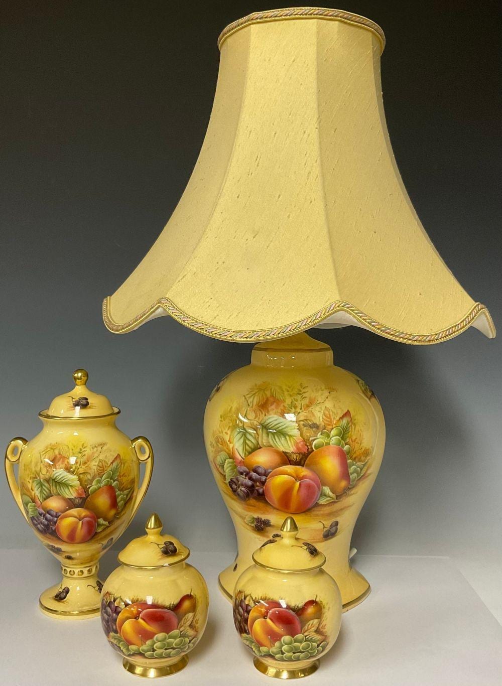 An Aynsley Orchard Gold pattern two-handled pedestal vase, 23cm high; a pair of Aynsley Orchard Gold ginger jars; an Aynsley Orchard Gold pattern lamp, 56cm high including shade (4) sold by Bamfords Auctioneers and Valuers Ltd, lot 72 — auction record photograph