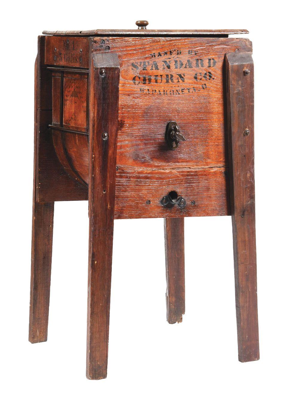 Antique wooden butter churn cabinet with open door showing the interior, dark metal latch and handle, and carved lettering on the front panel.