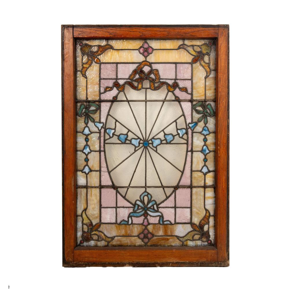 Framed stained glass window panel with a central circular design and floral accents in blue, pink, and yellow.