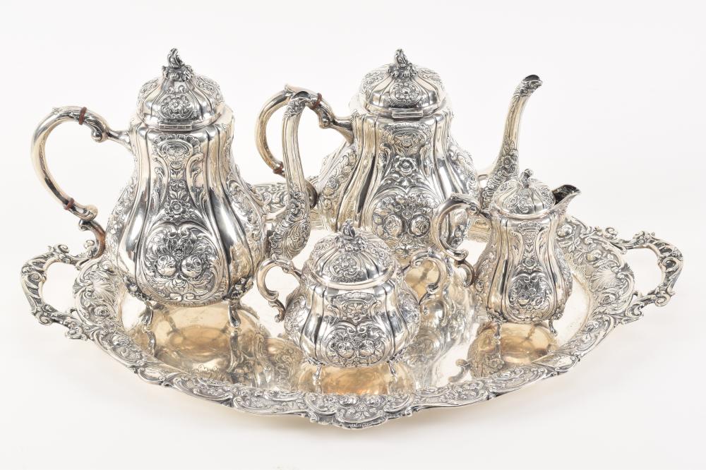 Auction comp thumbnail for German sterling silver heavy 5-piece tea set with tray. Ornate floral repousse decoration. Coffee pot: 9.75in high. Several tiny pin sized dents scattered. Tea pot: 8in high. Tiny pin dent in side. Creamer: one foot b... (Tremont Auctions, Lot 11)