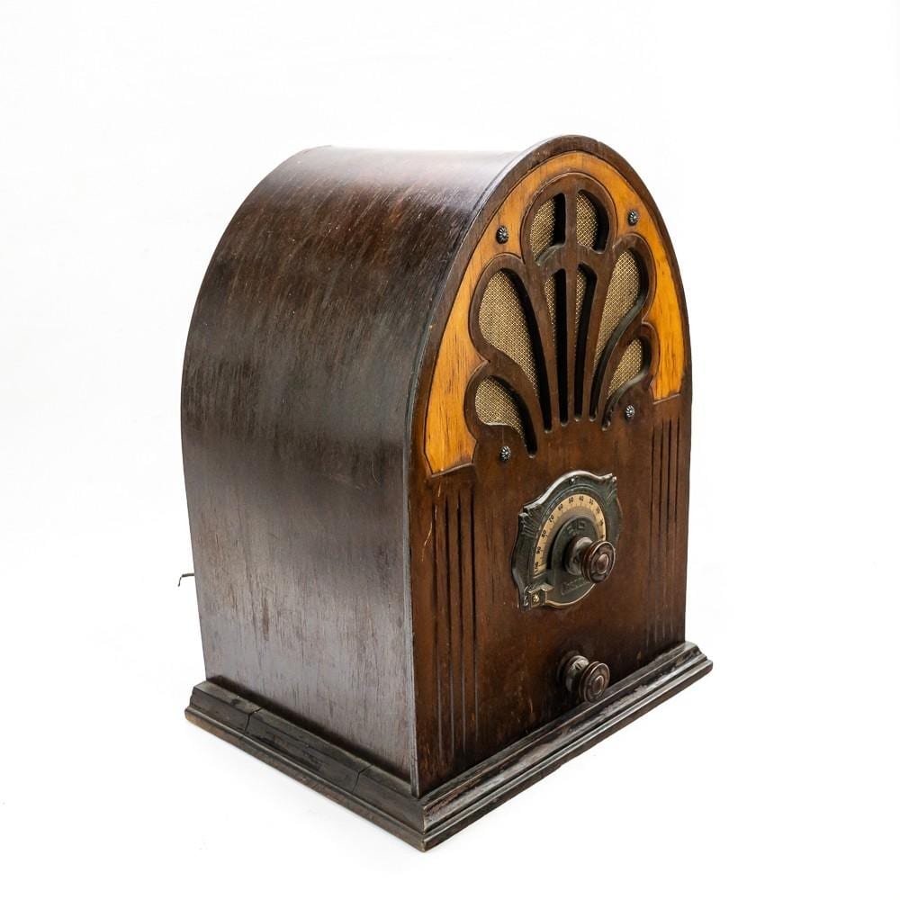 Vintage wooden tabletop radio with a rounded cabinet and arched speaker grille, shown from a front three-quarter angle.