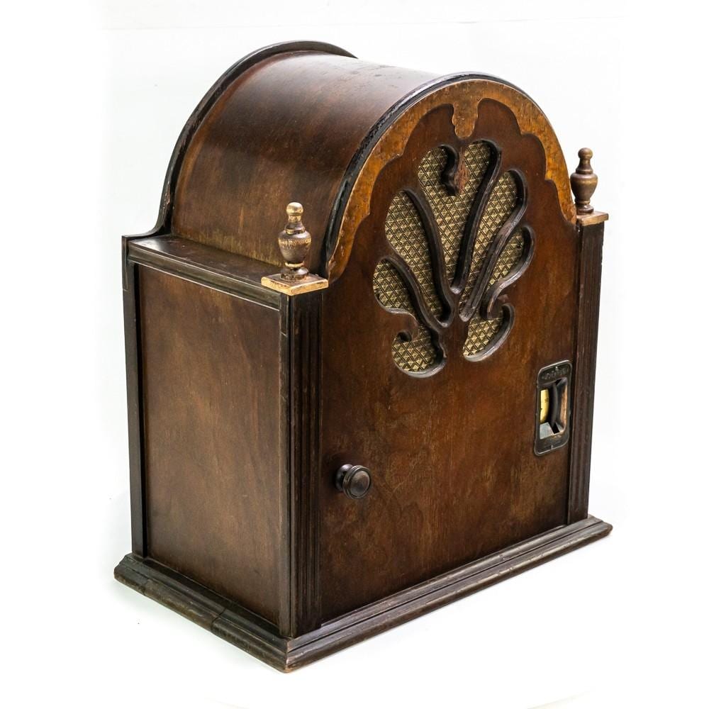 Brown wooden cathedral-style radio cabinet with arched speaker grille, tuning knob, and decorative finial on top.