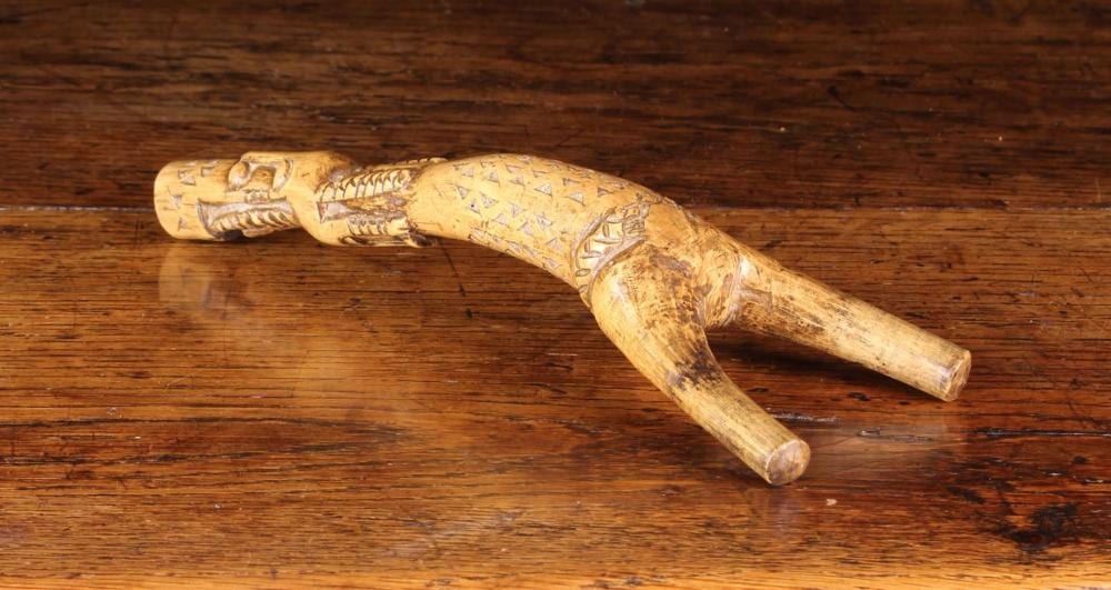 Wooden folk art carving shaped like a forked tree branch with carved decorative patterns and painted designs on a surface.