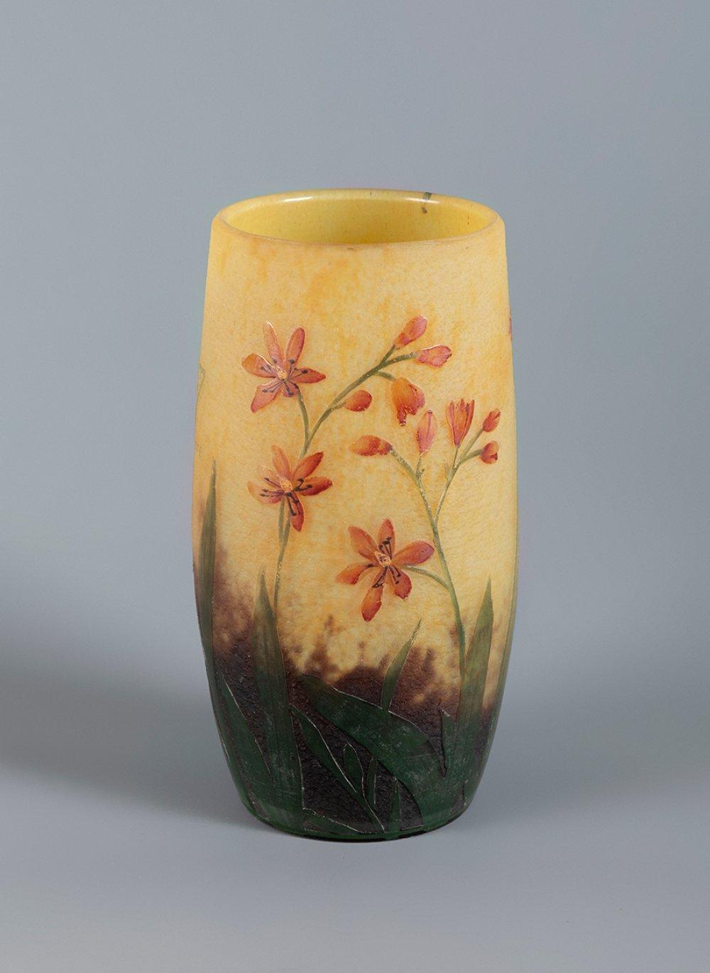 Art glass vase with a flared rim, decorated with pink orange flowers and green leaves on a yellow background and darker base