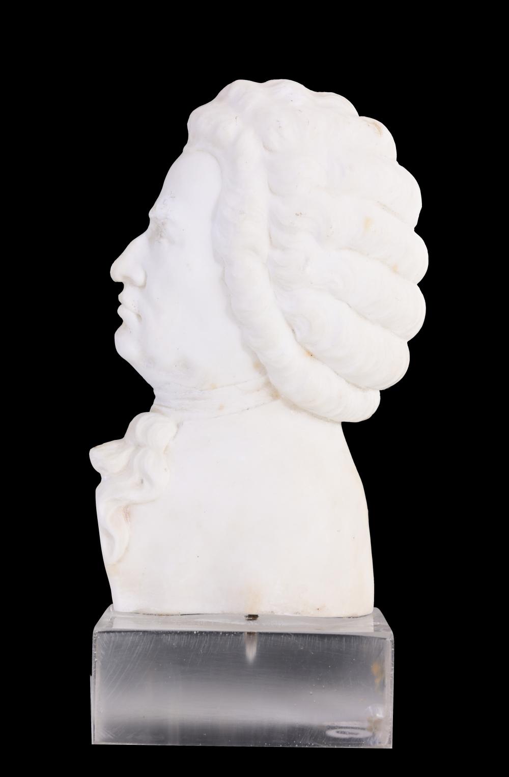 White marble bust sculpture of a man in profile, with curly hair and a draped cloak, shown against a black background.
