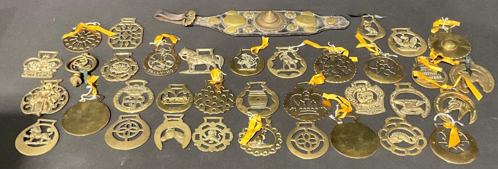 Assorted brass horse harness brasses and decorative metal ornaments laid on a dark surface.